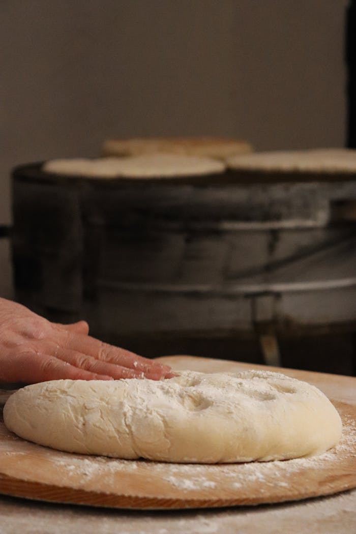 Bakers hand preparing fresh dough in a traditional bakery setting.