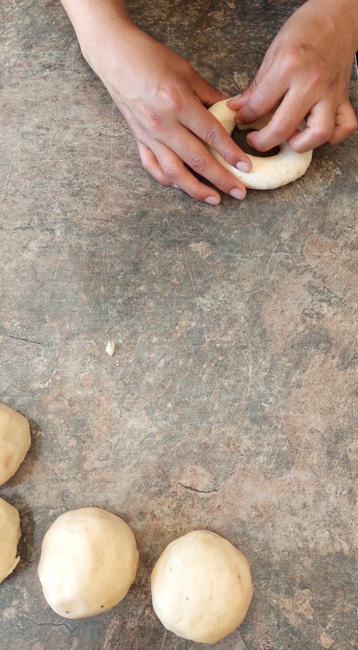 Hands shaping dough on a rustic surface, ready for baking. Perfect stock photo for culinary themes.