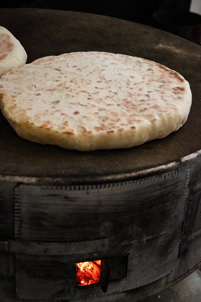 Close-up of flatbreads baking on a traditional tandoor, showcasing rustic culinary technique.
